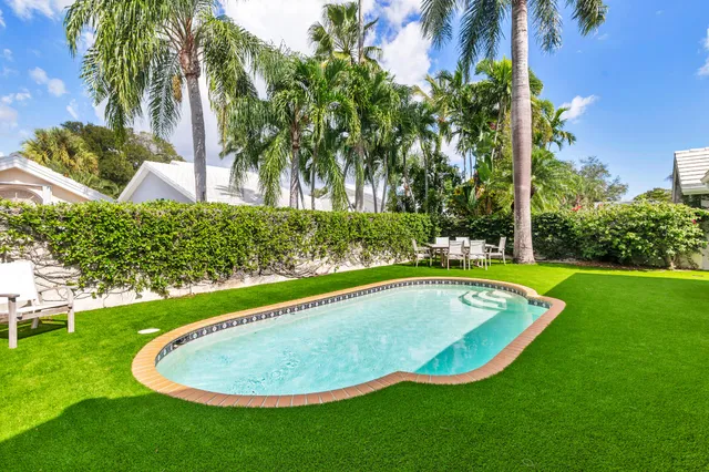 a view of a swimming pool with a yard and palm trees