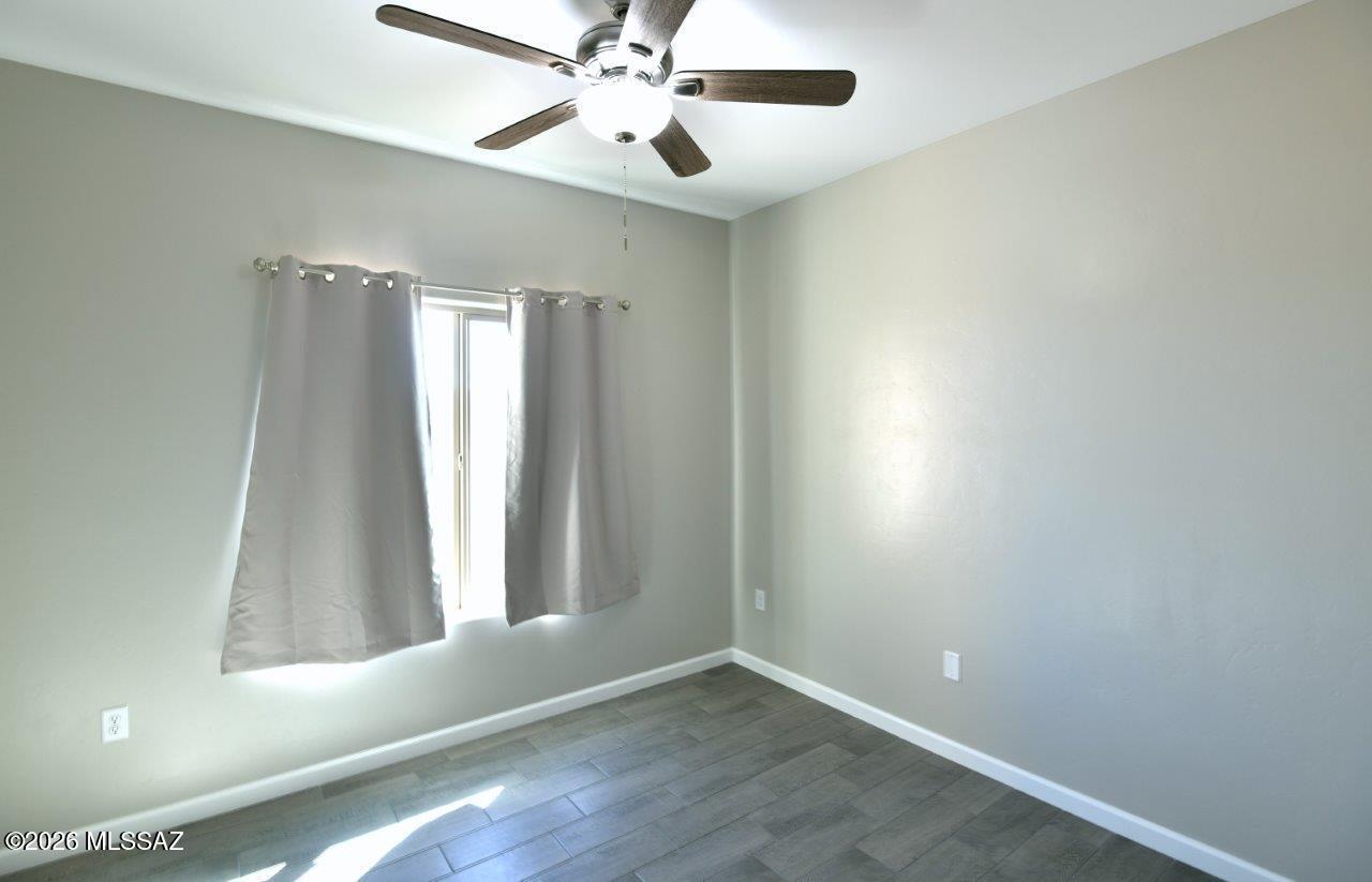 1091 North Vail View Road Vail, AZ 85641 - Photo 32 of 43 an empty room with wooden floor fan and windows