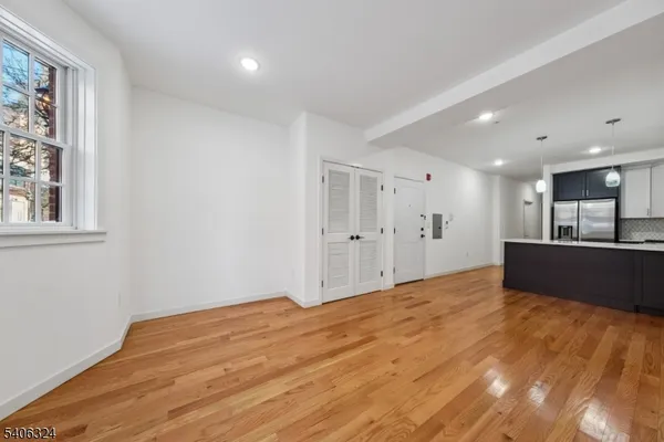 a view of kitchen and empty room with wooden floor