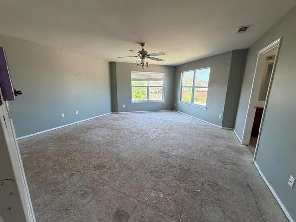 en empty room with windows and ceiling fan