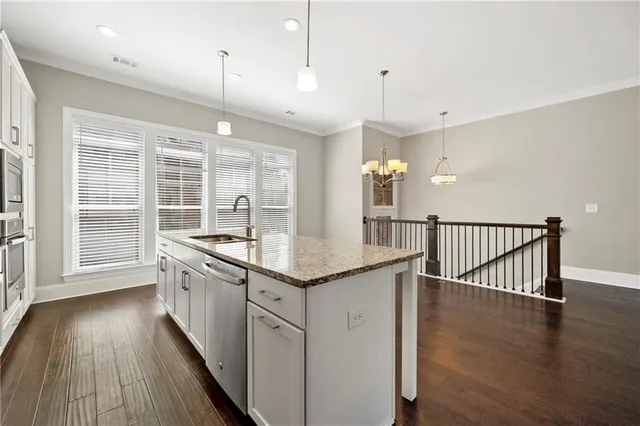 a kitchen with granite countertop a stove a sink and wooden floors