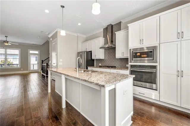 a kitchen with stainless steel appliances granite countertop a lot of counter space and wooden floors