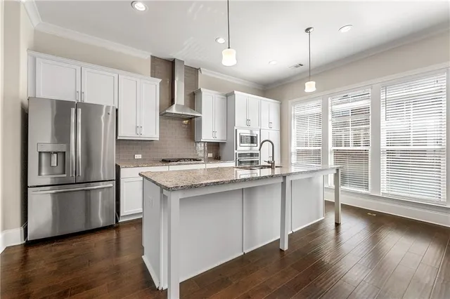 a kitchen with stainless steel appliances granite countertop a refrigerator a sink dishwasher a stove and white countertops with wooden floor