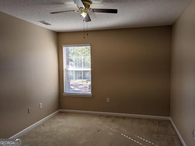 an empty room with a window and a fan