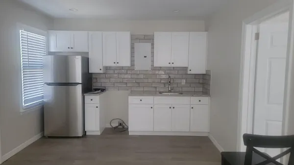 a kitchen with white cabinets and refrigerator
