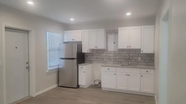 a kitchen with granite countertop white cabinets and refrigerator