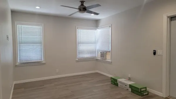 a view of an empty room with wooden floor and a window