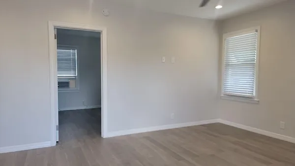 an empty room with wooden floor and windows