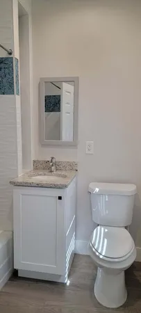 a bathroom with a granite countertop toilet a sink and a mirror