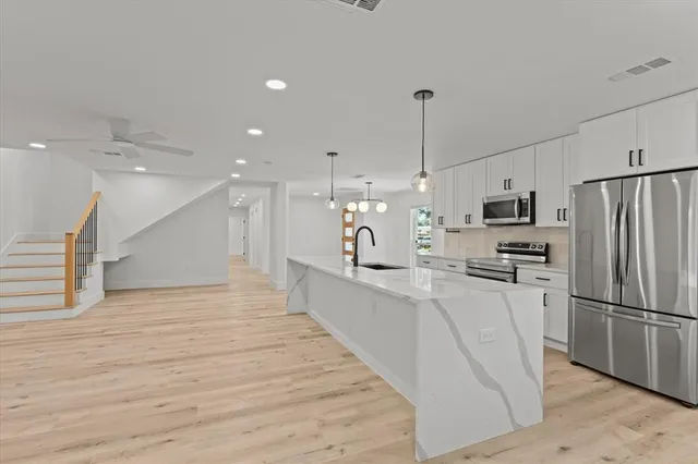 a large kitchen with kitchen island a sink stainless steel appliances and cabinets