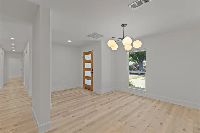 an empty room with wooden floor cabinet and windows