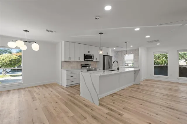 a large white kitchen with lots of counter space a sink appliances and cabinets