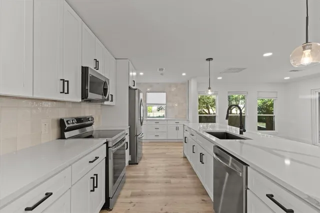 a large kitchen with stainless steel appliances lots of counter space and a sink