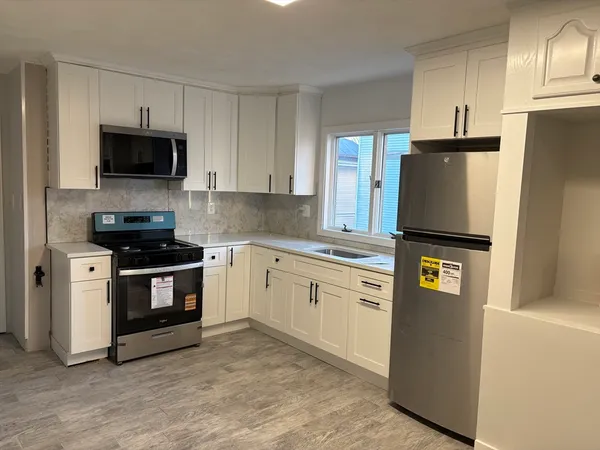 a kitchen with granite countertop a refrigerator stove and microwave