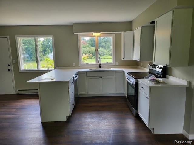 10089 Coldwater Road Flushing, MI 48433 - Photo 16 of 17 Kitchen featuring white cabinetry, light-toned countertops, a built-in dishwasher, and dark wood-finish flooring