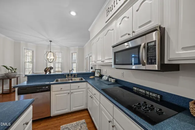 a kitchen with granite countertop a sink a stove cabinets and wooden floor