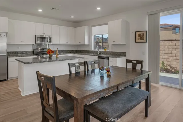 a kitchen with stainless steel appliances granite countertop a refrigerator a stove a sink and white cabinets