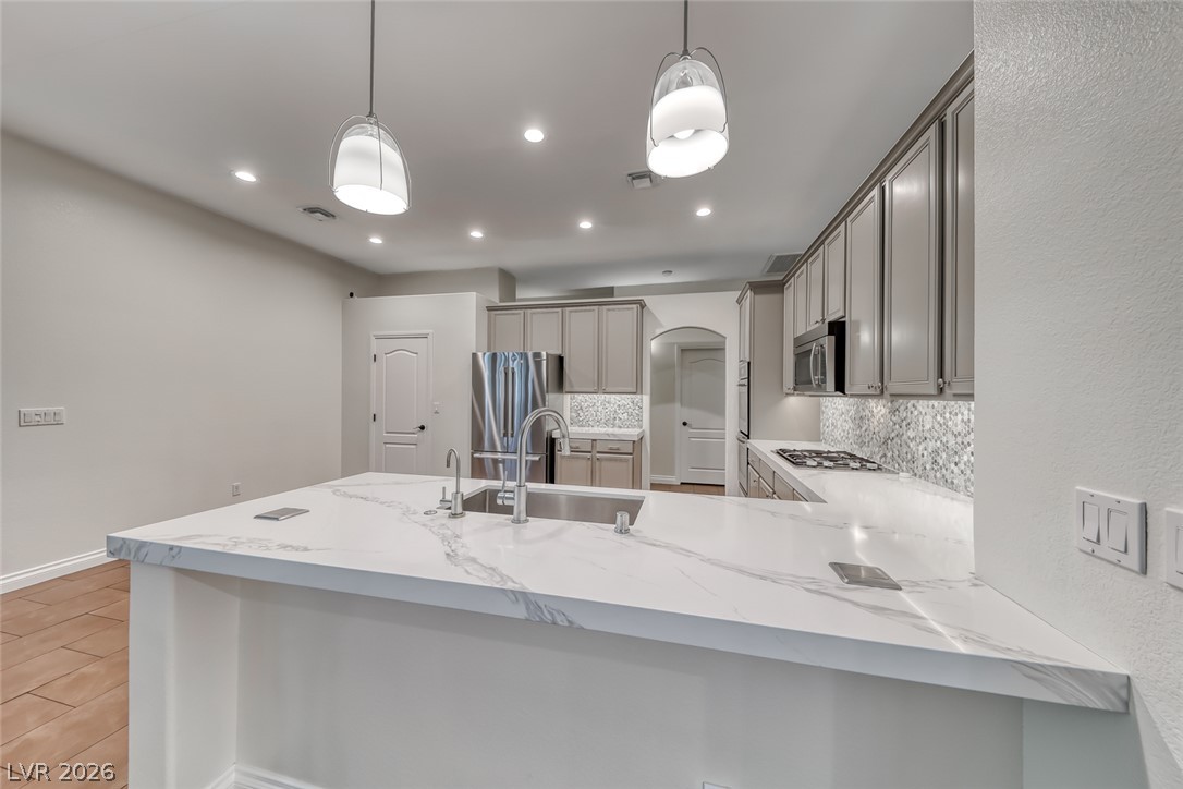 2122 Mooreview Street Henderson, NV 89012 - Photo 8 of 44 A well-appointed kitchen showcasing a spacious island with a sink and sleek stainless steel appliances.
