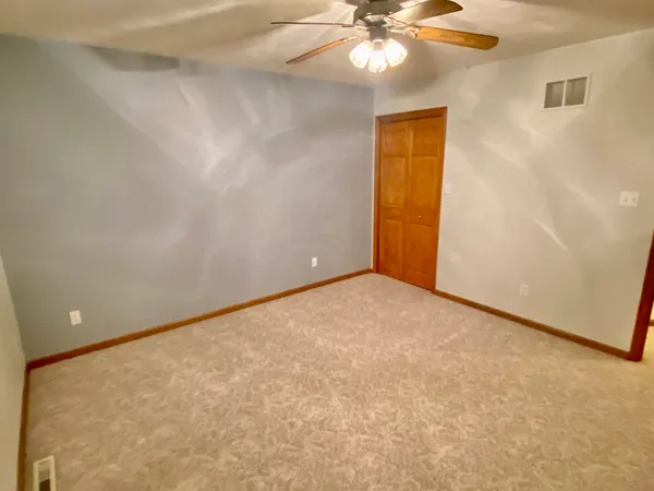 a view of an empty room with a chandelier fan