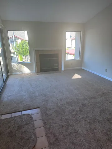 an empty room with windows and fireplace