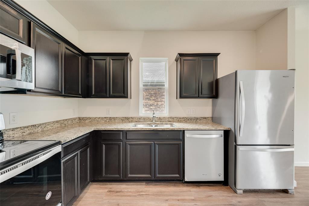 708 Peach Tree Lane Anna, TX 75409 - Photo 14 of 32 a kitchen with stainless steel appliances granite countertop a refrigerator and a sink