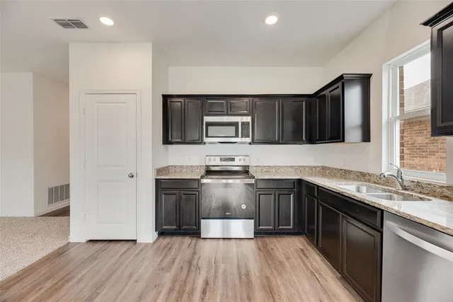 a kitchen with stainless steel appliances granite countertop wooden cabinets a stove top oven a sink and dishwasher