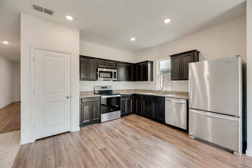 708 Peach Tree Lane Anna, TX 75409 - Photo 16 of 32 a kitchen with stainless steel appliances granite countertop a refrigerator stove a sink and a microwave with wooden floor