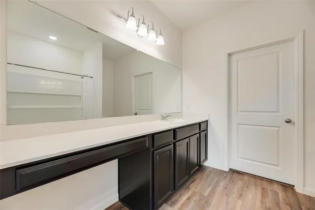 a hallway with a sink a mirror and wooden floor