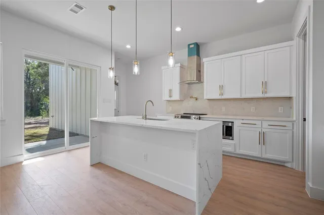 a large kitchen with cabinets wooden floor and a sink