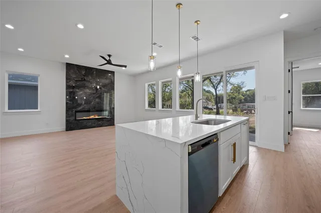 a kitchen with stainless steel appliances granite countertop a sink a stove and a wooden floors