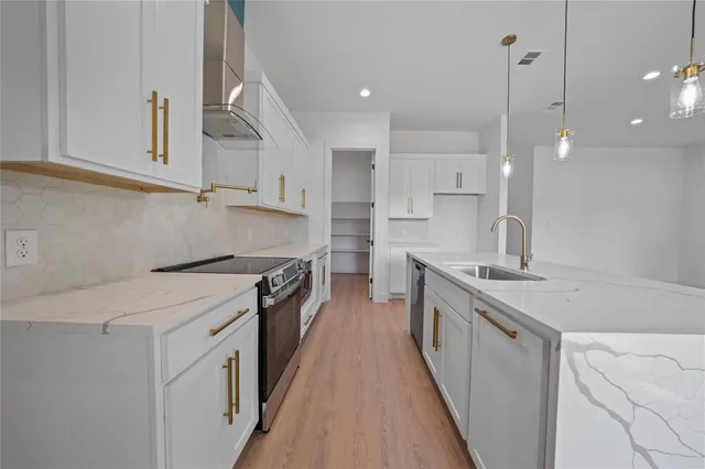 a kitchen with stainless steel appliances granite countertop a sink a stove and a refrigerator