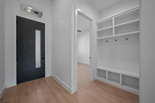 a view of an empty room with wooden floor and closet