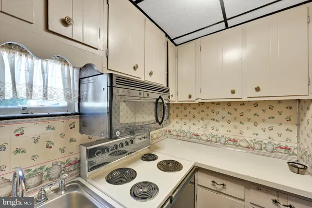 a kitchen with granite countertop a sink a stove and cabinets