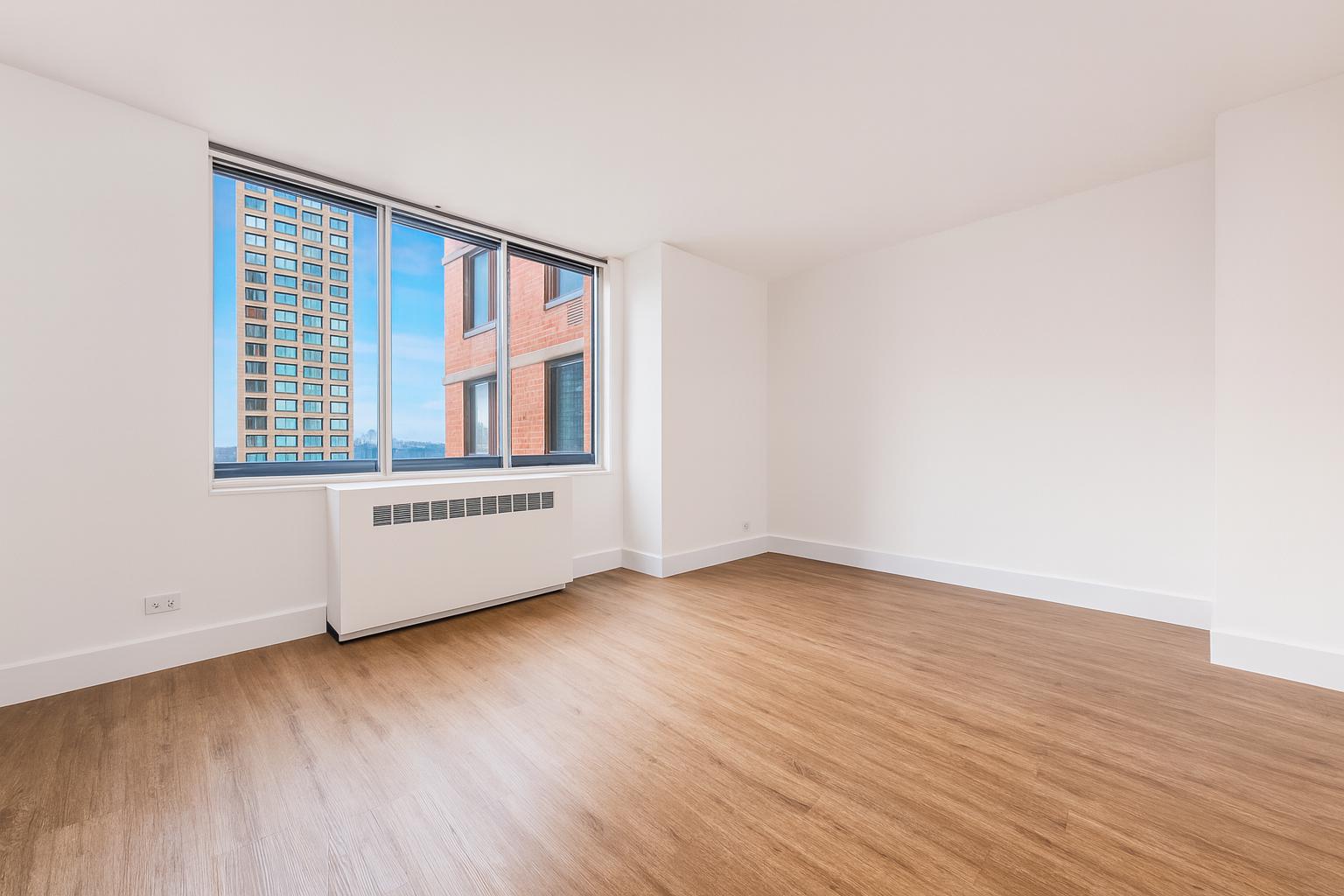 1735 York Avenue, Unit 12H Manhattan, NY 10128 - Photo 5 of 23 a view of an empty room with wooden floor and a window
