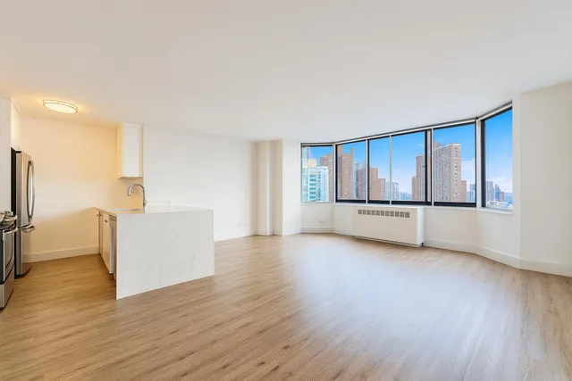 a view of a big room with wooden floor and windows