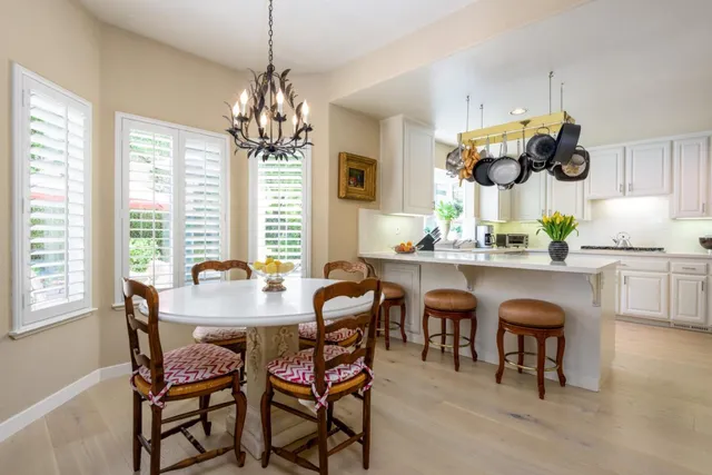 a kitchen with stainless steel appliances a dining table chairs sink and microwave