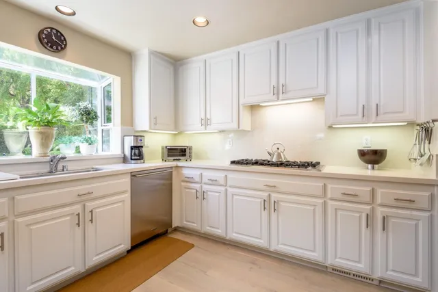 a kitchen with white cabinets white stove and sink