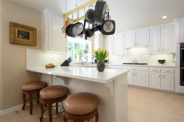 a kitchen with a stove cabinets and chairs