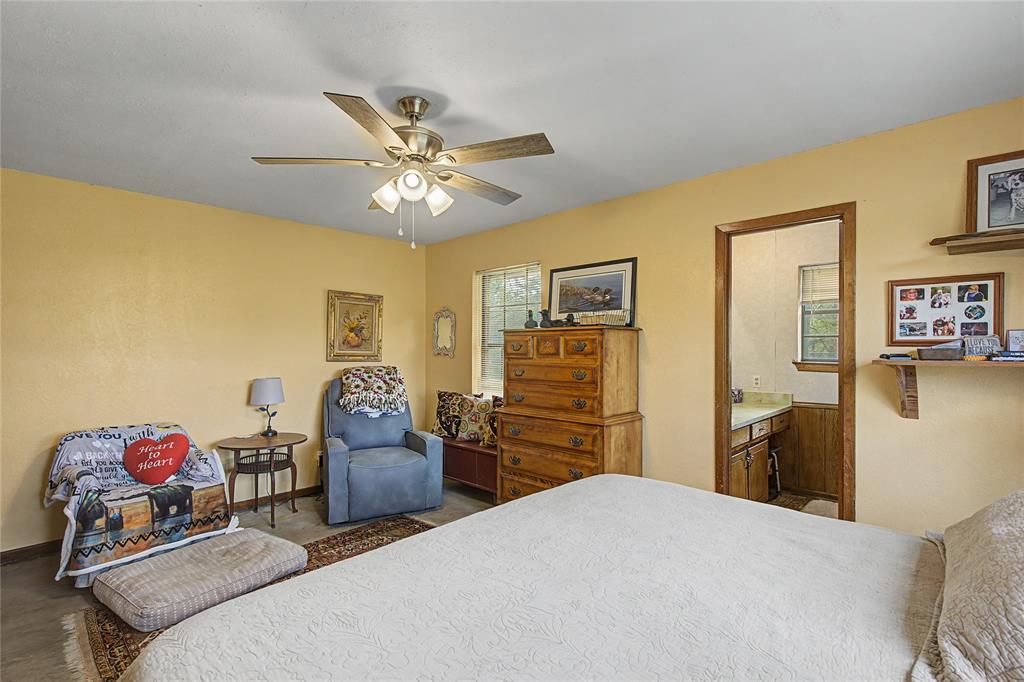 243 County Road 3851 Poolville, TX 76487 - Photo 17 of 34 a bedroom with a bed and dresser with the mirror