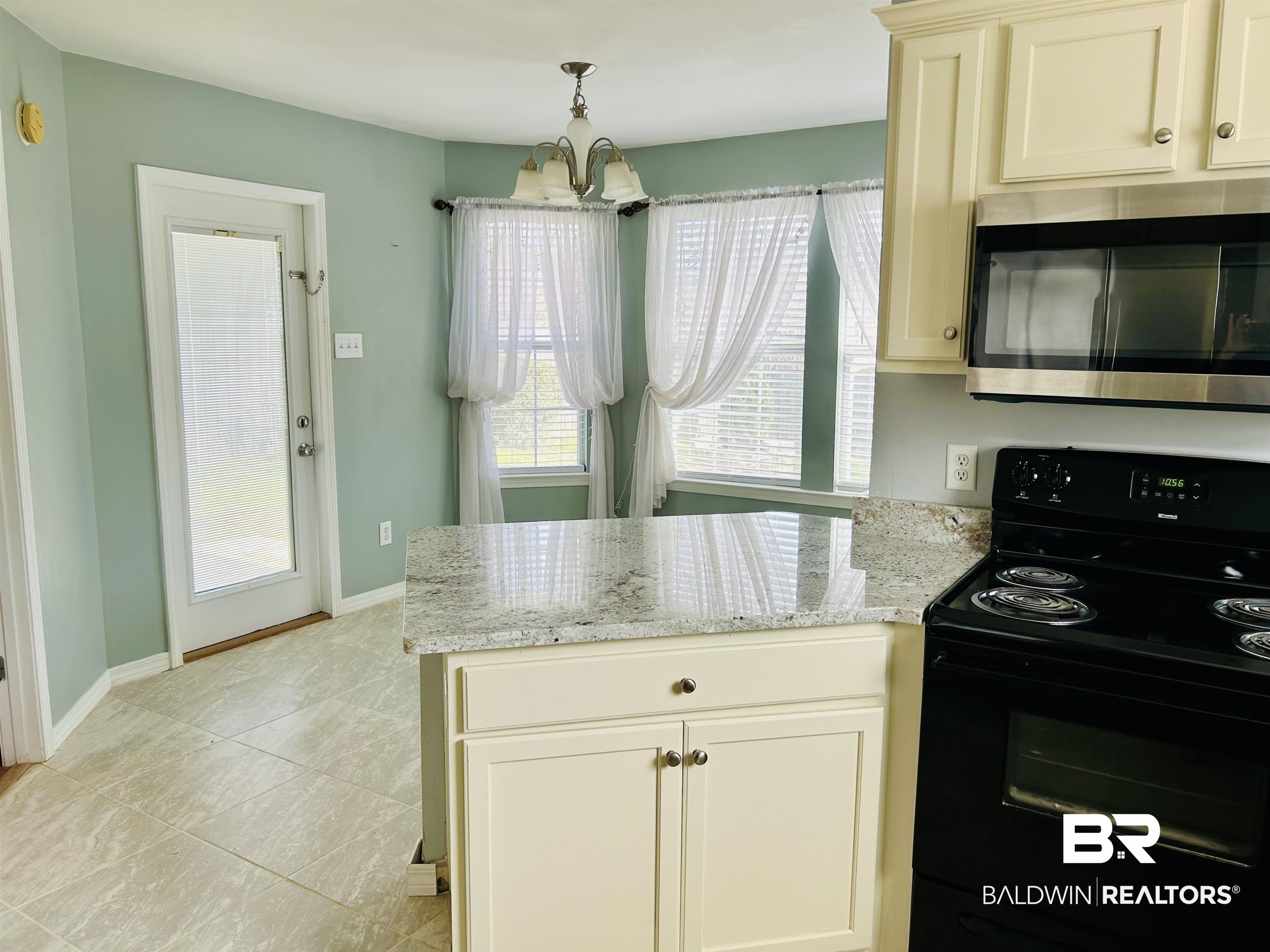 919 Parliament Court Mobile, AL 36695 - Photo 9 of 19 Kitchen with light stone counters, decorative light fixtures, black range with electric cooktop, and a notable chandelier