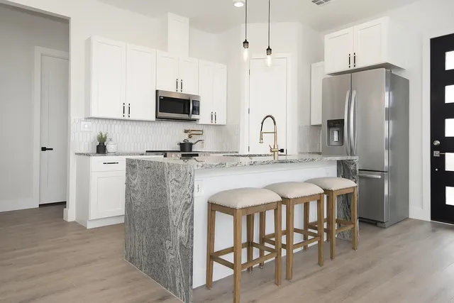 a kitchen with stainless steel appliances granite countertop a table chairs refrigerator a sink and dishwasher