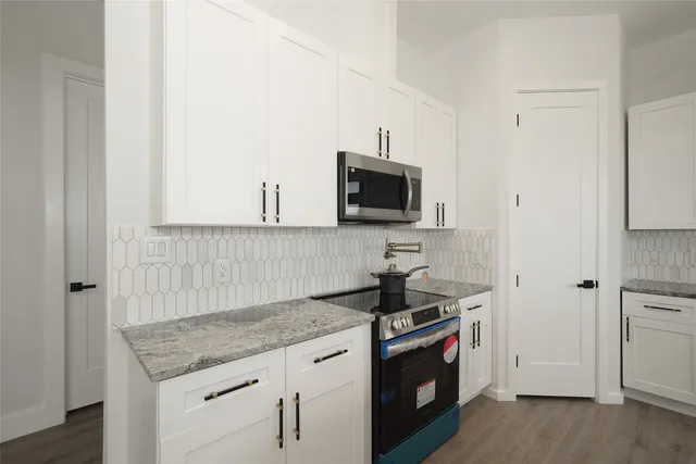 a kitchen with granite countertop a sink stove and refrigerator