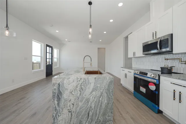 a large kitchen with stainless steel appliances granite countertop a stove a sink dishwasher and a microwave with wooden floor