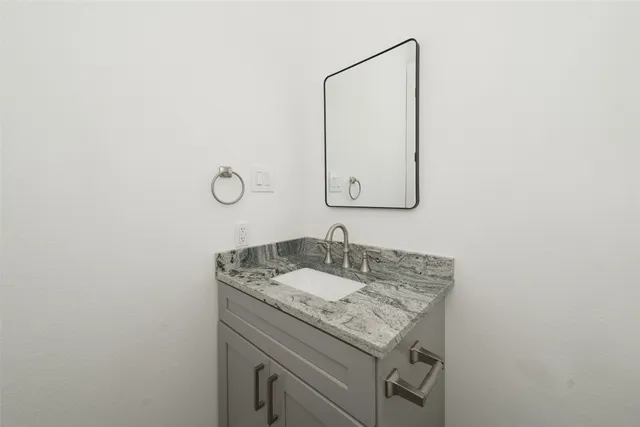 a bathroom with a granite countertop sink and a mirror