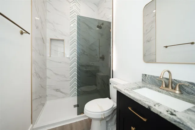 a bathroom with a granite countertop toilet sink shower and mirror
