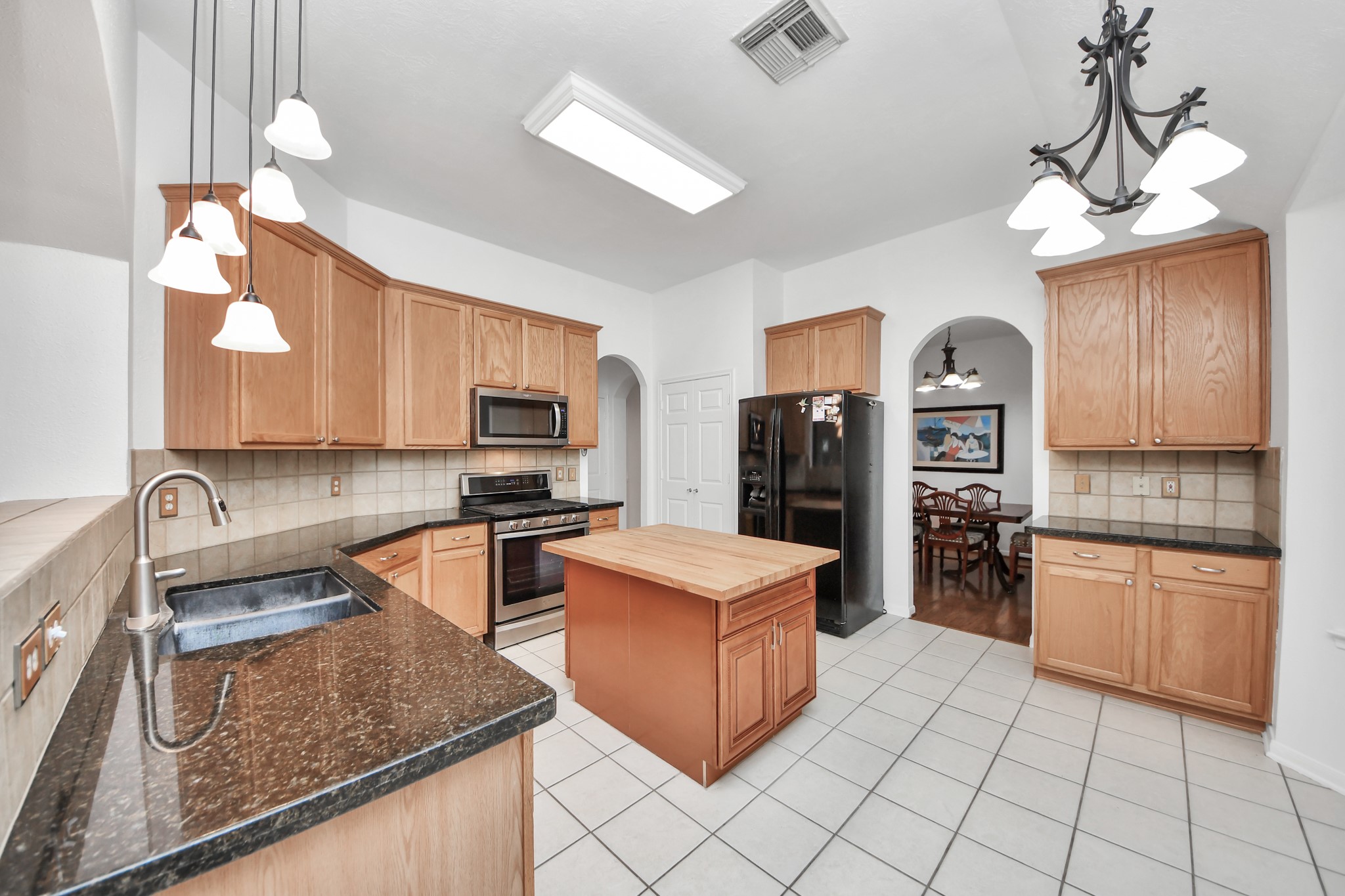 5622 Pineaster Pointe Lane Spring, TX 77379 - Photo 14 of 40 Kitchen featuring light wood cabinetry, dark speckled countertops, and a central island with a wood countertop