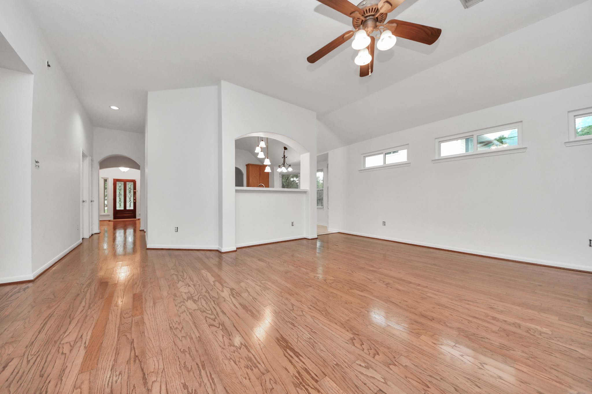 5622 Pineaster Pointe Lane Spring, TX 77379 - Photo 18 of 40 Spacious living area featuring wood-finish flooring, vaulted ceilings, and a ceiling fan with integrated lighting