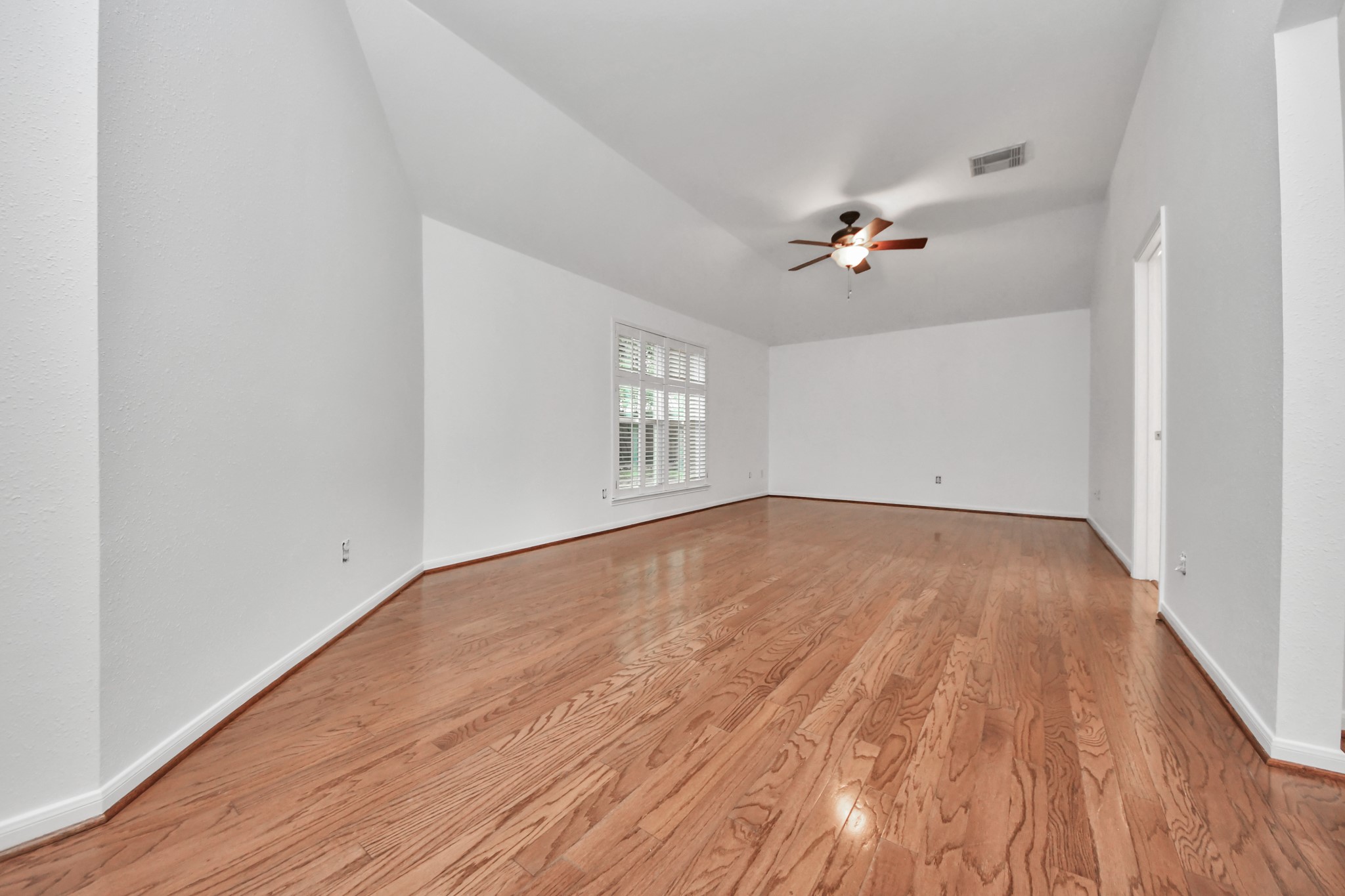 5622 Pineaster Pointe Lane Spring, TX 77379 - Photo 19 of 40 Expansive room featuring hardwood flooring, white baseboards, a multi-pane window with white blinds, a ceiling fan, and vaulted ceilings