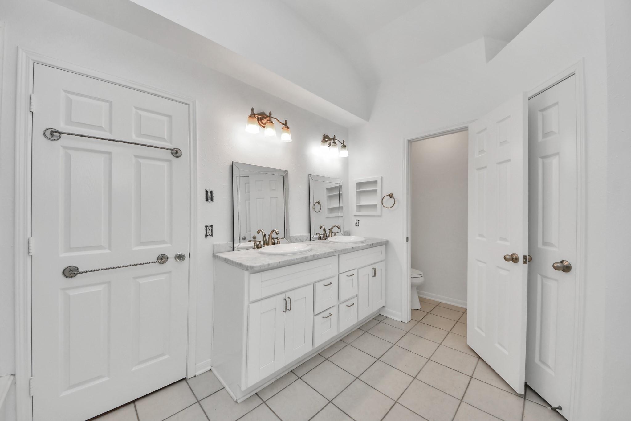 5622 Pineaster Pointe Lane Spring, TX 77379 - Photo 22 of 40 Dual sink vanity with white cabinetry, light-toned countertop, and brass-finish fixtures