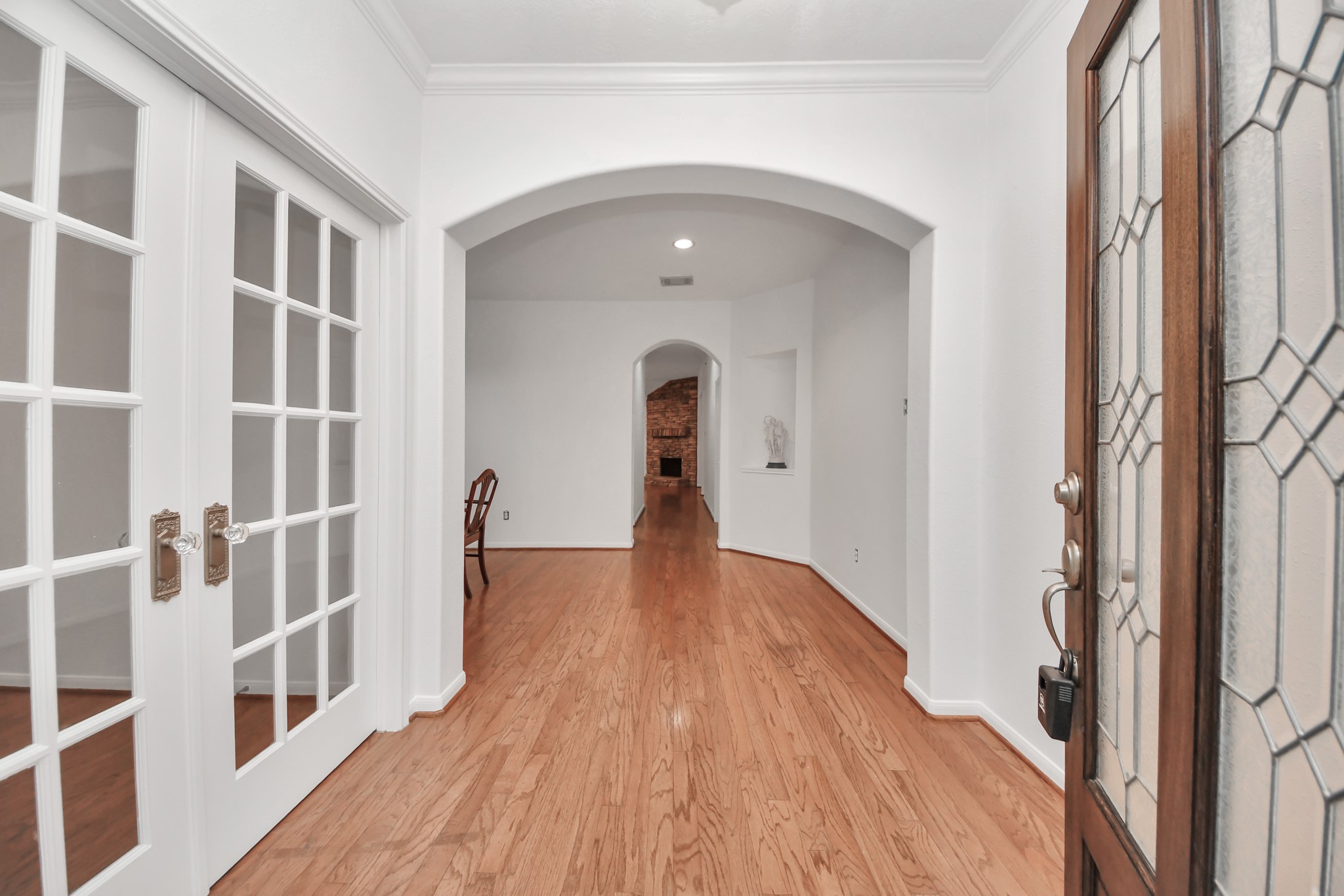 5622 Pineaster Pointe Lane Spring, TX 77379 - Photo 5 of 40 Entryway featuring hardwood flooring, white French doors, an arched doorway, crown molding, and a leaded glass front door